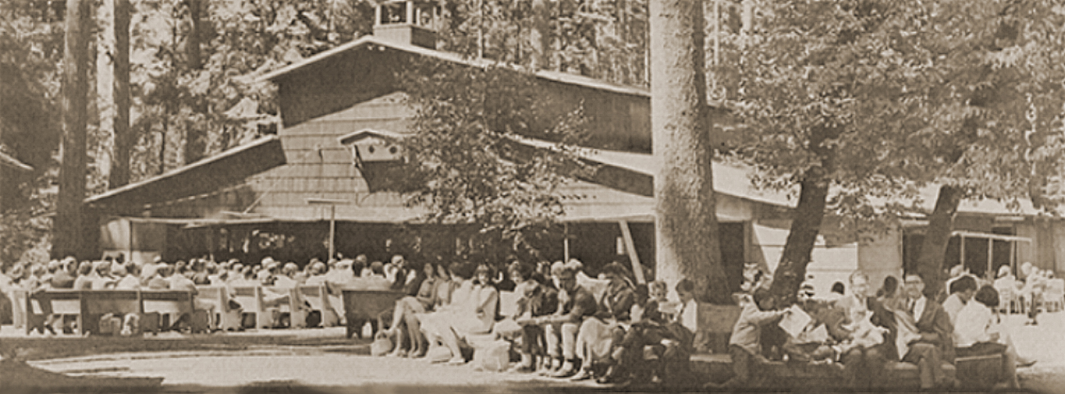 Historic photograph of a crowd seated on benches outside Canby Grove’s original Tabernacle